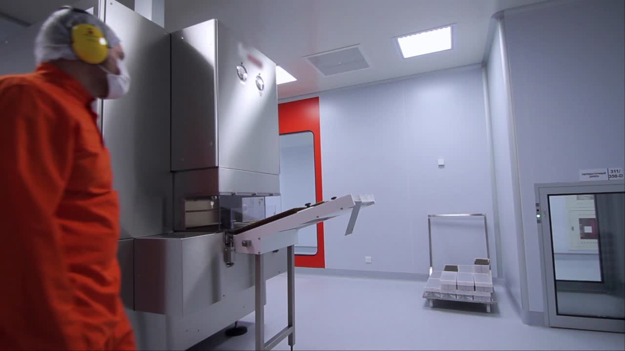 trabajador de fábrica que comienza a trabajar con una máquina de envasado farmacéutico en la fábrica