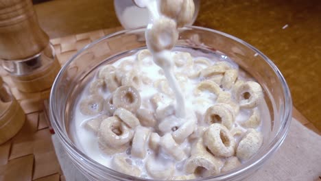 copos de avena crujientes en un tazón para un delicioso desayuno matutino con leche. cámara lenta con toma de seguimiento de rotación.