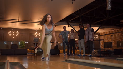 multi ethnic group of friends in a bowling club a woman throws a ball and knocks out a strike