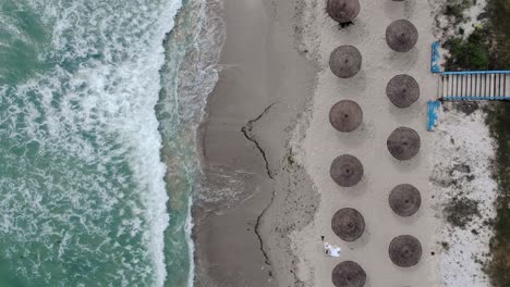 bird's eye view over beach with parasols on the shore in vama veche, romania - drone shot