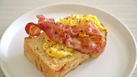pan tostado con huevos revueltos y tocino en un plato blanco