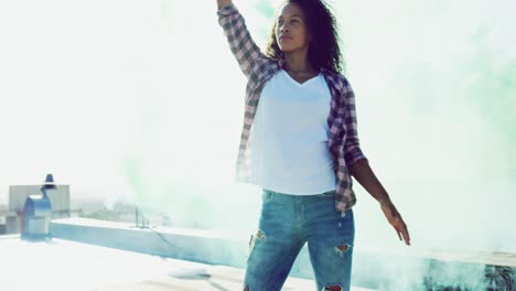 Fashionable-young-woman-on-urban-rooftop-using-a-smoke-grenade