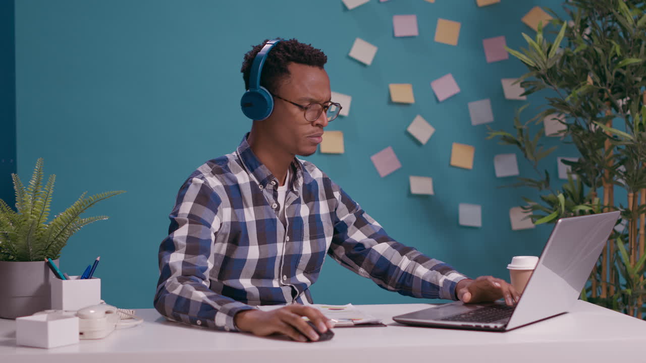 Funcionário de escritório ouvindo música e cantando enquanto usa o notebook