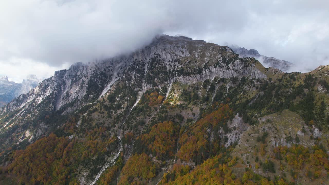 hermosa montaña con pico alto bajo las nubes y bosque colorido en otoño