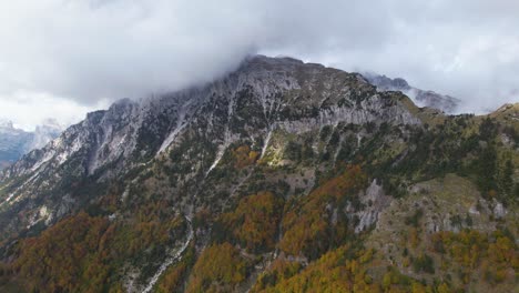 Hermosa-Montaña-Con-Pico-Alto-Bajo-Las-Nubes-Y-Bosque-Colorido-En-Otoño