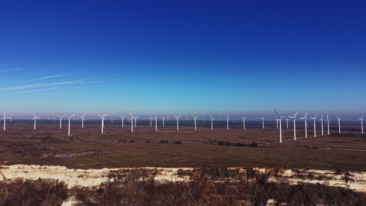 Turbine eoliche in un grande campo aperto sotto un cielo azzurro limpido