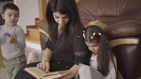 una hermosa mujer de oriente medio leyendo el libro a los niños pequeños.