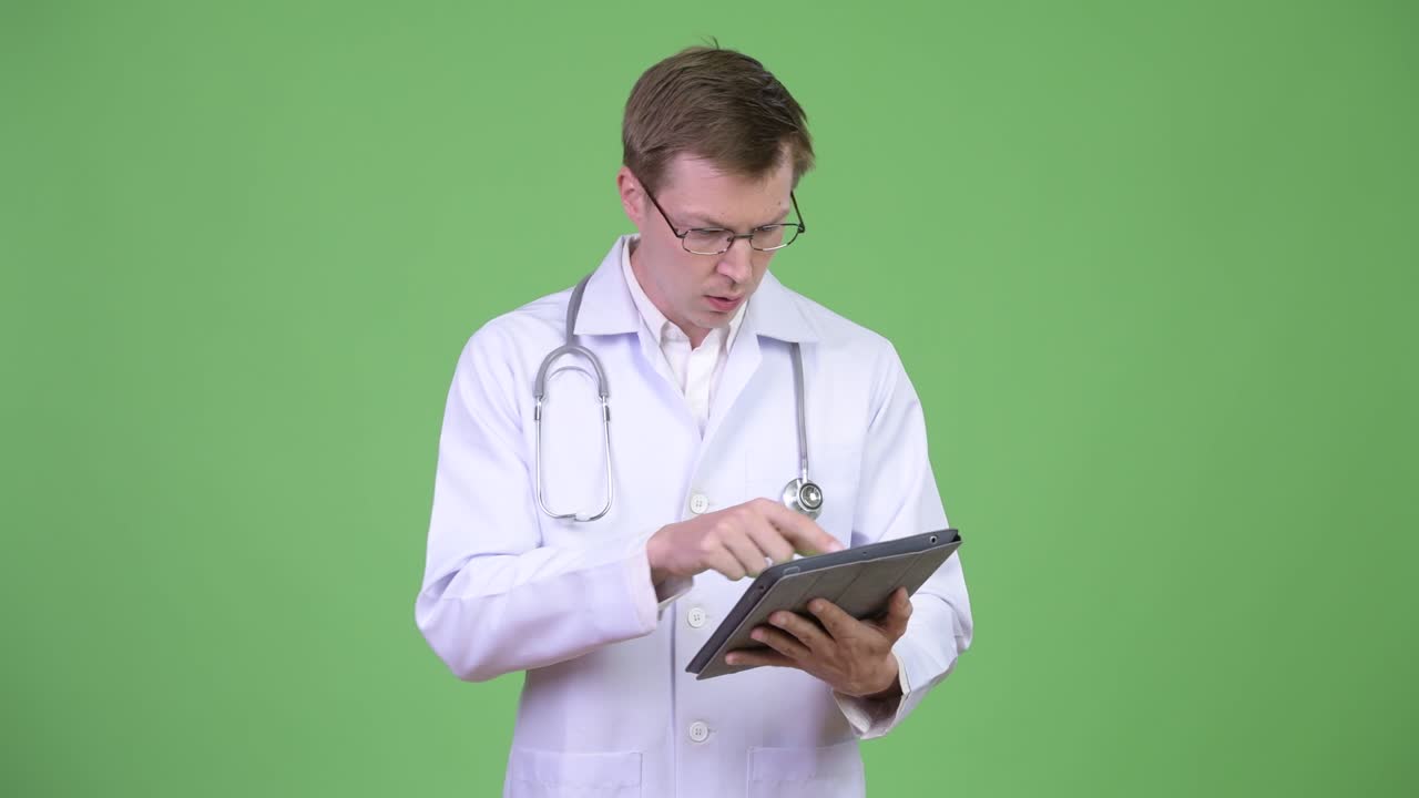 Medico uomo che parla e sembra scioccato mentre usa un tablet digitale