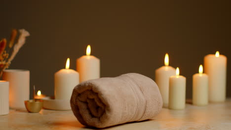 person, die eine robe trägt und ein handtuch bei einem entspannenden spa-tag mit angezündeten kerzen, getrocknetem gras und weihrauch aufnimmt