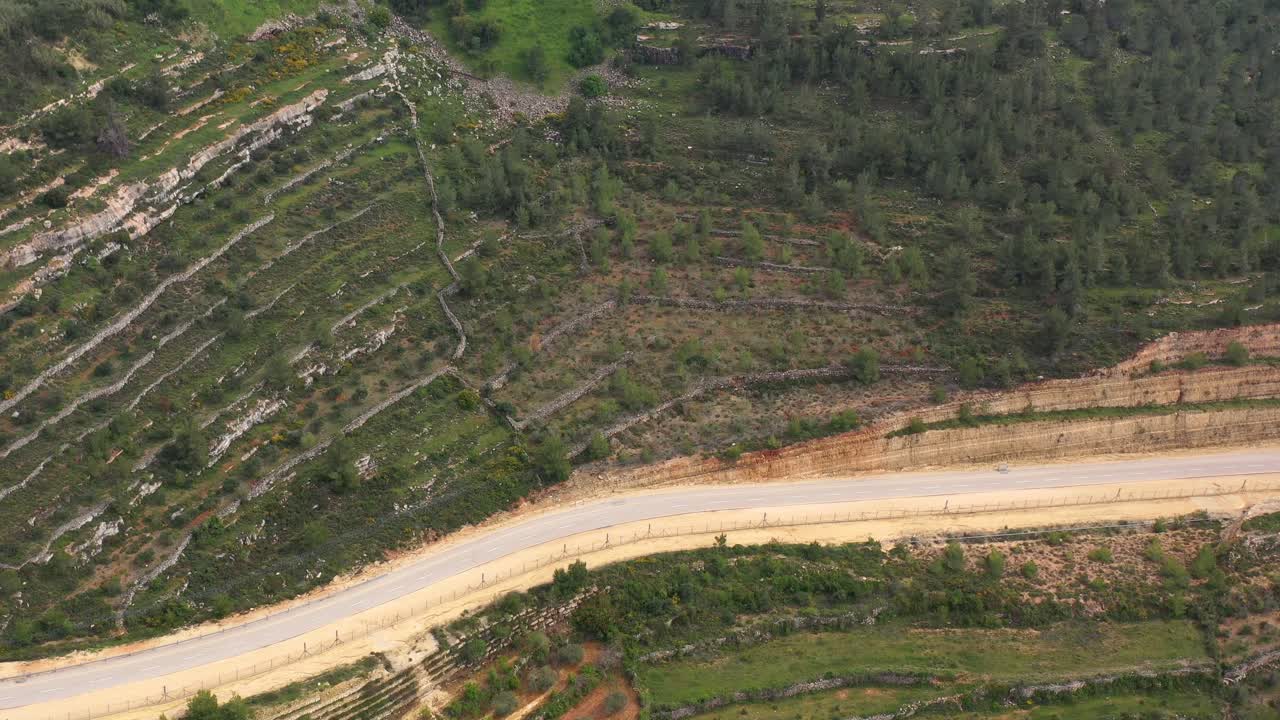 Aerial View of Terraced Agricultural Fields and Winding Road Through Hills