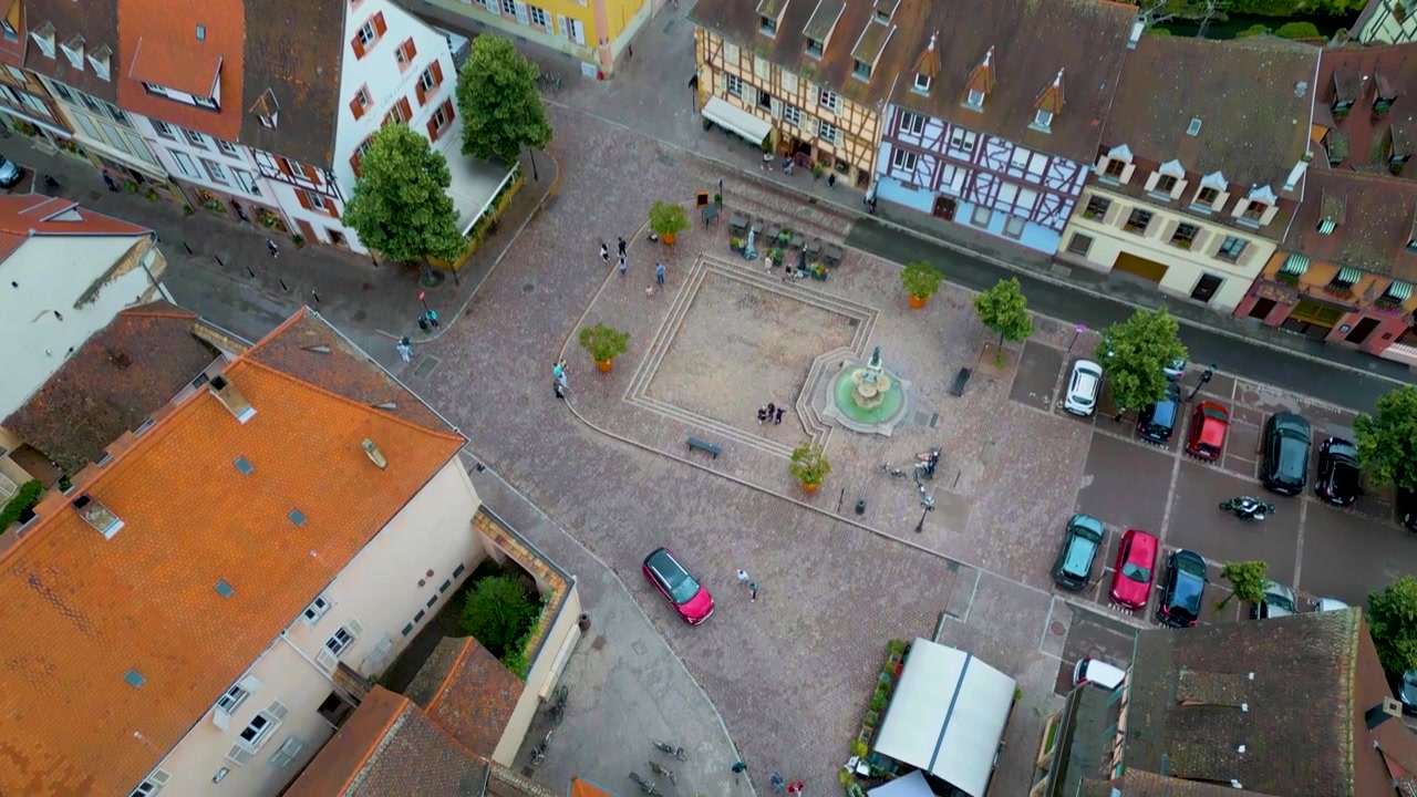 Video aereo con drone in 4K di turisti che camminano tra le case a graticcio e gli edifici storici lungo il fiume Lauch nella zona della Piccola Venezia di Colmar, Francia.
