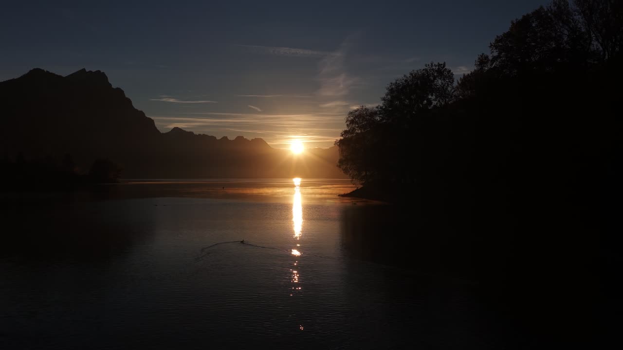 A peaceful dusk scene over Walensee, Schweiz. Silhouetted mountains frame the water, reflecting the soft light of the twilight sky