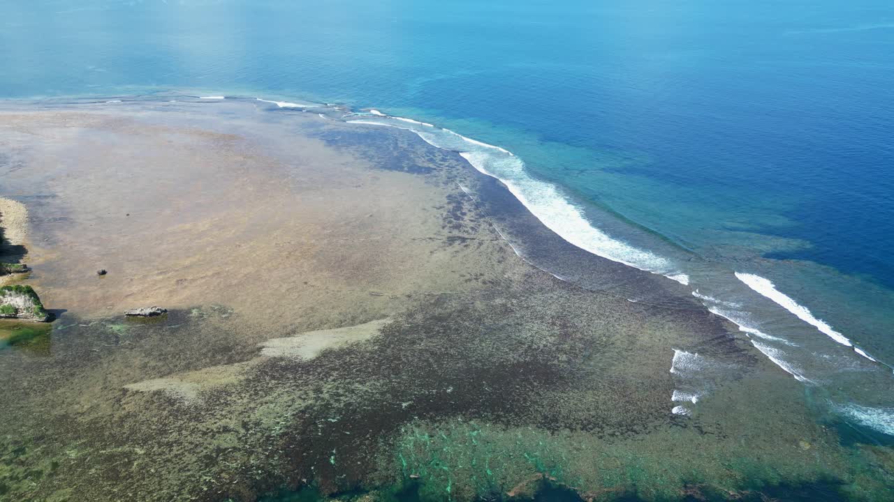 Stunning aerial dolly shot of coastal shallow reef with turquoise ocean waves crashing at Catanduanes, Philippines
