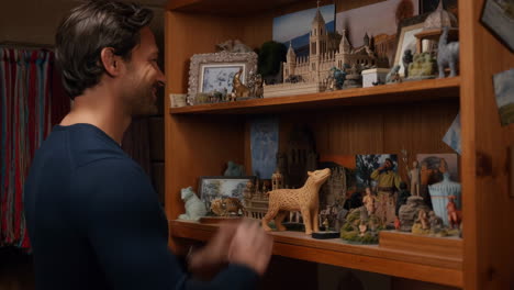 man arranging collectibles on a bookshelf