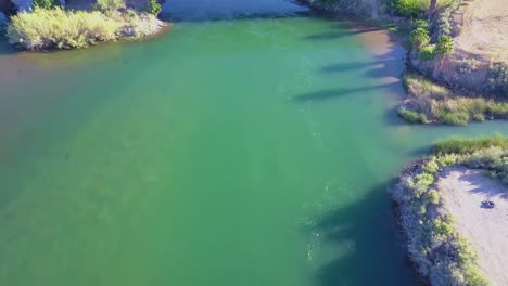 A-high-rising-aerial-over-the-Colorado-River-flowing-along-the-California-Arizona-border-with-trucks-crossing