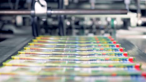 portions of coloured journals are getting collected from a conveyor belt by a person