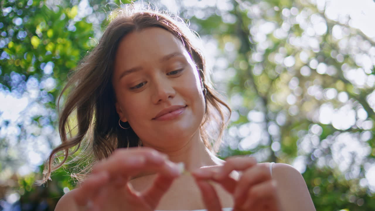 Primer plano de una chica adivinando el futuro con una margarita de pie en un bosque soleado. Mujer sosteniendo una flor