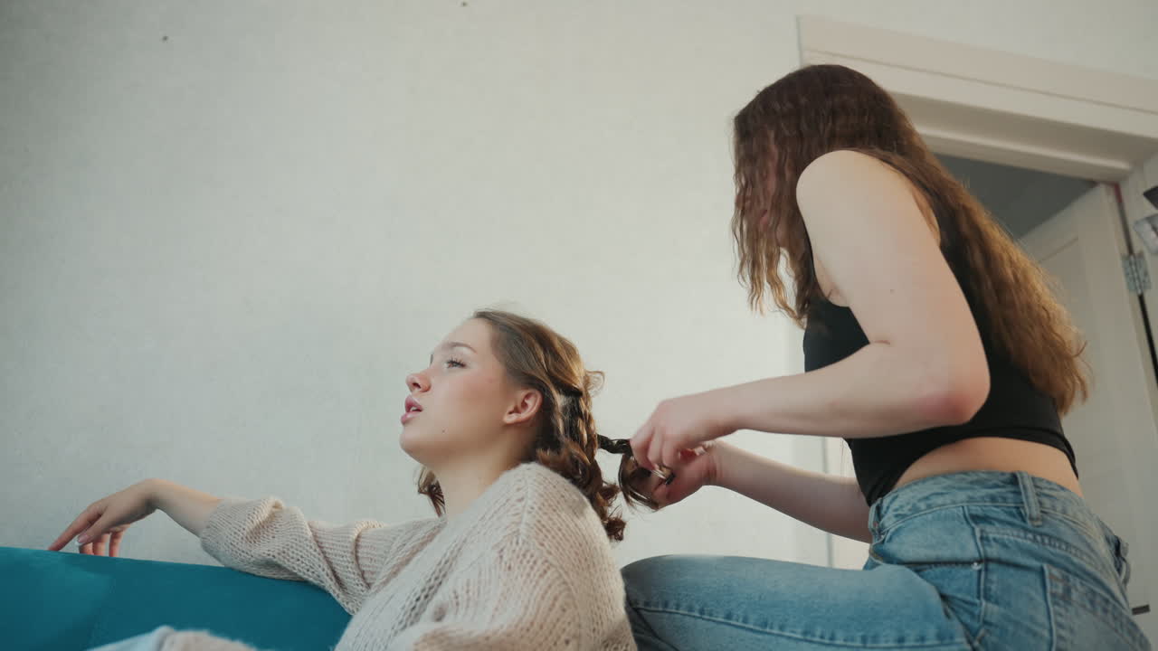 Relaxed Friend Styling, Friend Enjoying Casual Braid Conversation Scene, Chill Afternoon With Friend Braiding Hair Near Sofa, Comfortable Day Spent With Friend Creating Braids And Chatting Easily