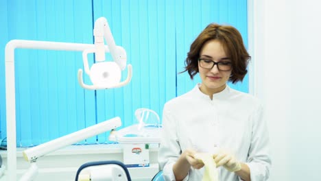 el dentista se pone guantes en el consultorio dental