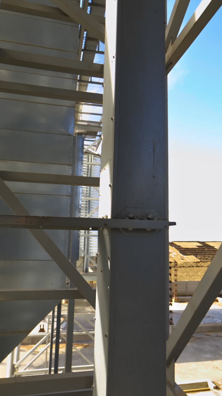 Modern warehouse. Metal frame on industrial plant. Grain elevator. Storage tanks with metal equipment outdoors. Vertical video