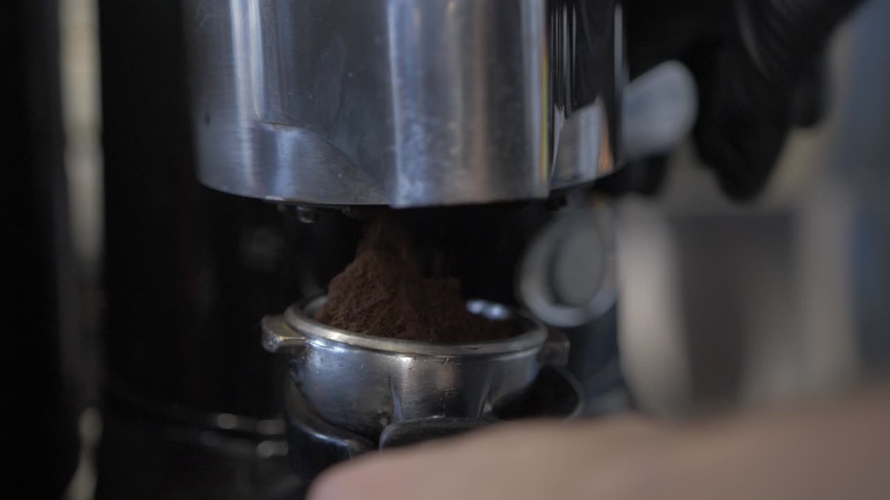커피 머신을 사용하여 커피 원두를 누르는 바리스타