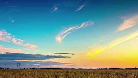 Vibrant-Sunset-Timelapse-with-Electric-Pylon-on-Horizon,-behind-field