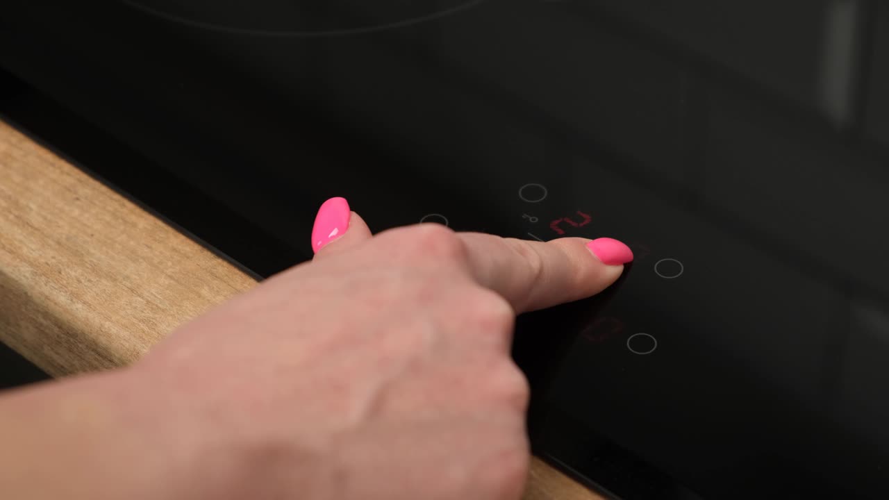 un primer plano de una mano femenina incluye una estufa de inducción. tecnología moderna. panel táctil de cocina eléctrica.