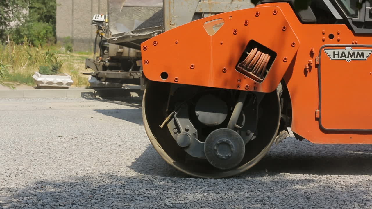 VINNITSA, UKRAINE - JULY 2017: Road roller laying gravel during road construction