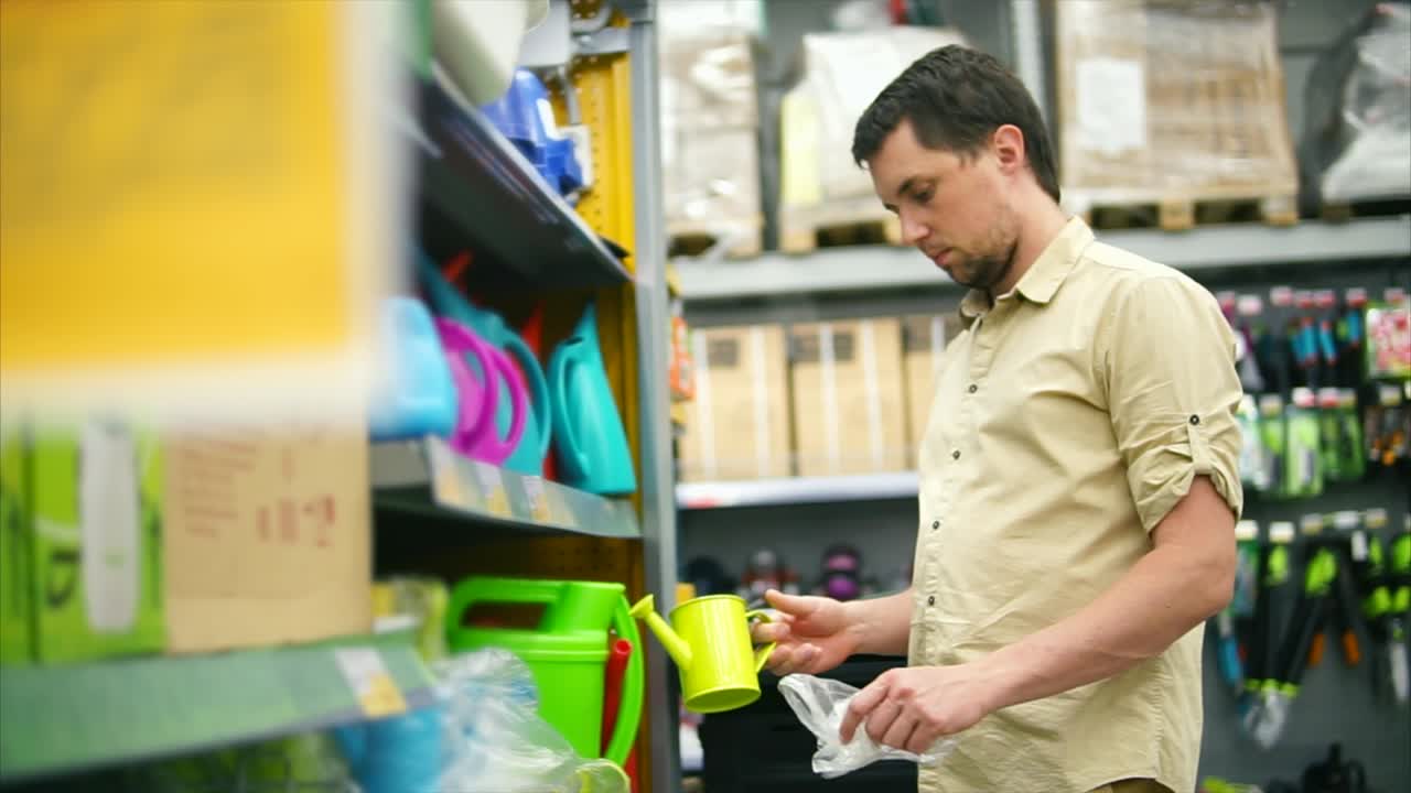 hombre de compras para regar puede en la tienda de suministros de jardín