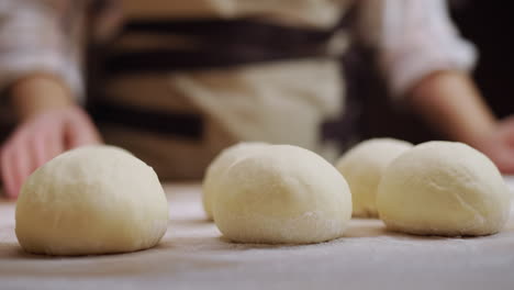 the baker rolls out the dough for buns on the board. working in a bakery. 4k video