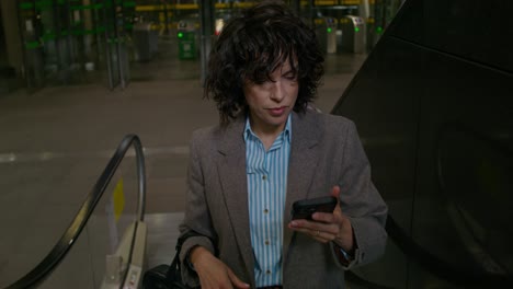 woman using phone on escalator in an airport terminal