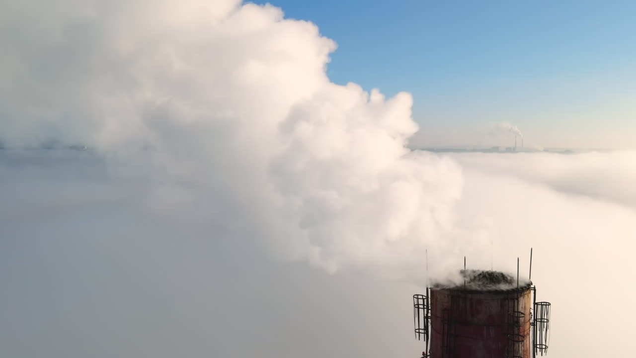 Aerial drone view of Chisinau. Tube of the thermal station with smoke coming out above the low clouds. Visible buildings. Moldova