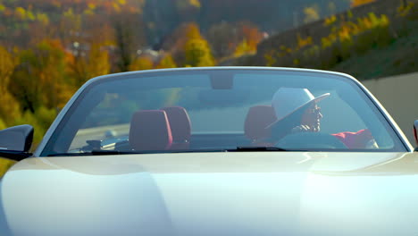 woman driving a convertible car on a scenic autumn road trip