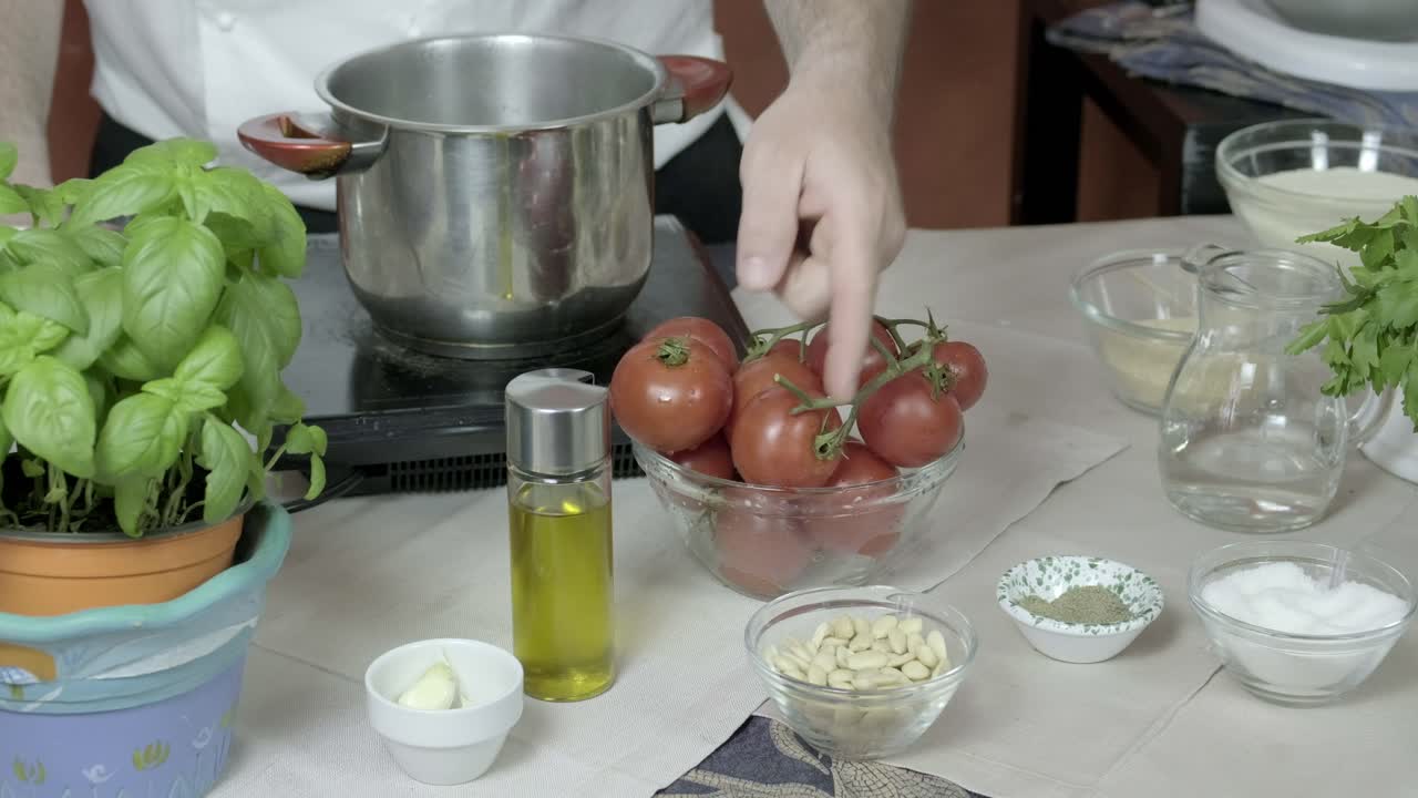 el chef señala las manos a varios ingredientes utilizados en la creación de una salsa de pesto básica