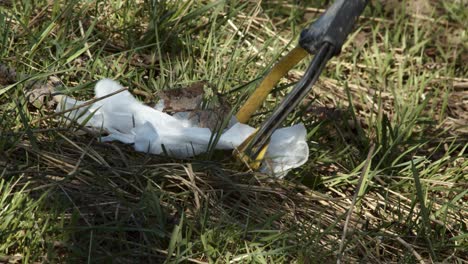 person gathering trash from lawn with a trash picking tool, close up