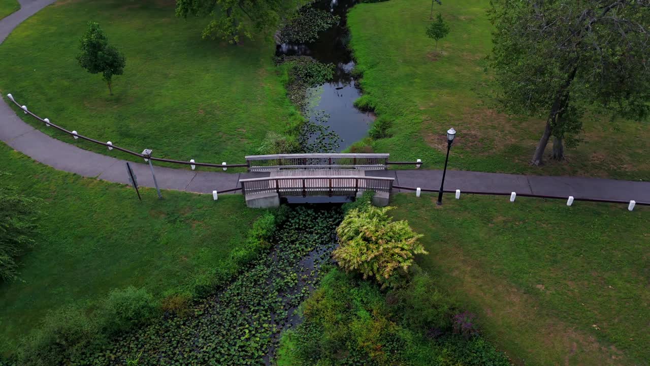 воздушный вид на пустой парк с зелеными пейзажами и отражающим потоком в облачный день