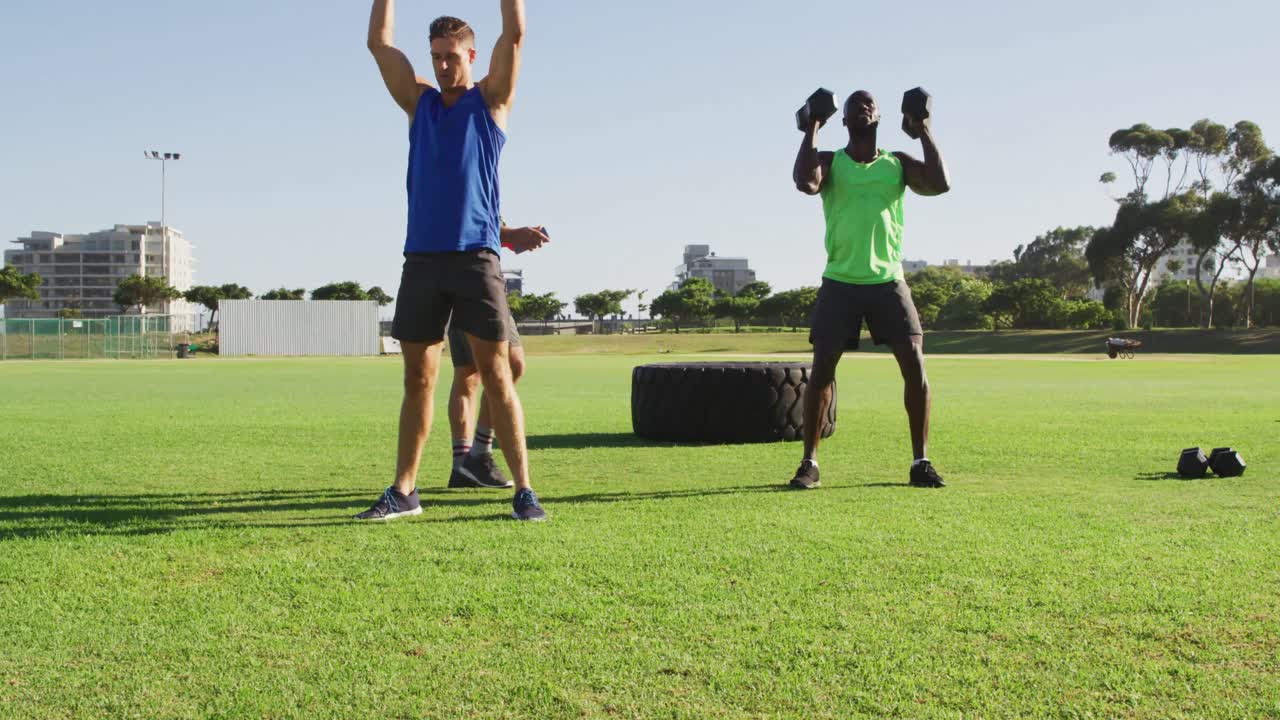 grupo diverso de dos hombres en forma y un entrenador masculino haciendo ejercicio al aire libre en cuclillas y levantando pesas