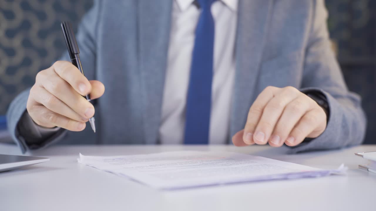 Close-up of businessman reading and signing contract.