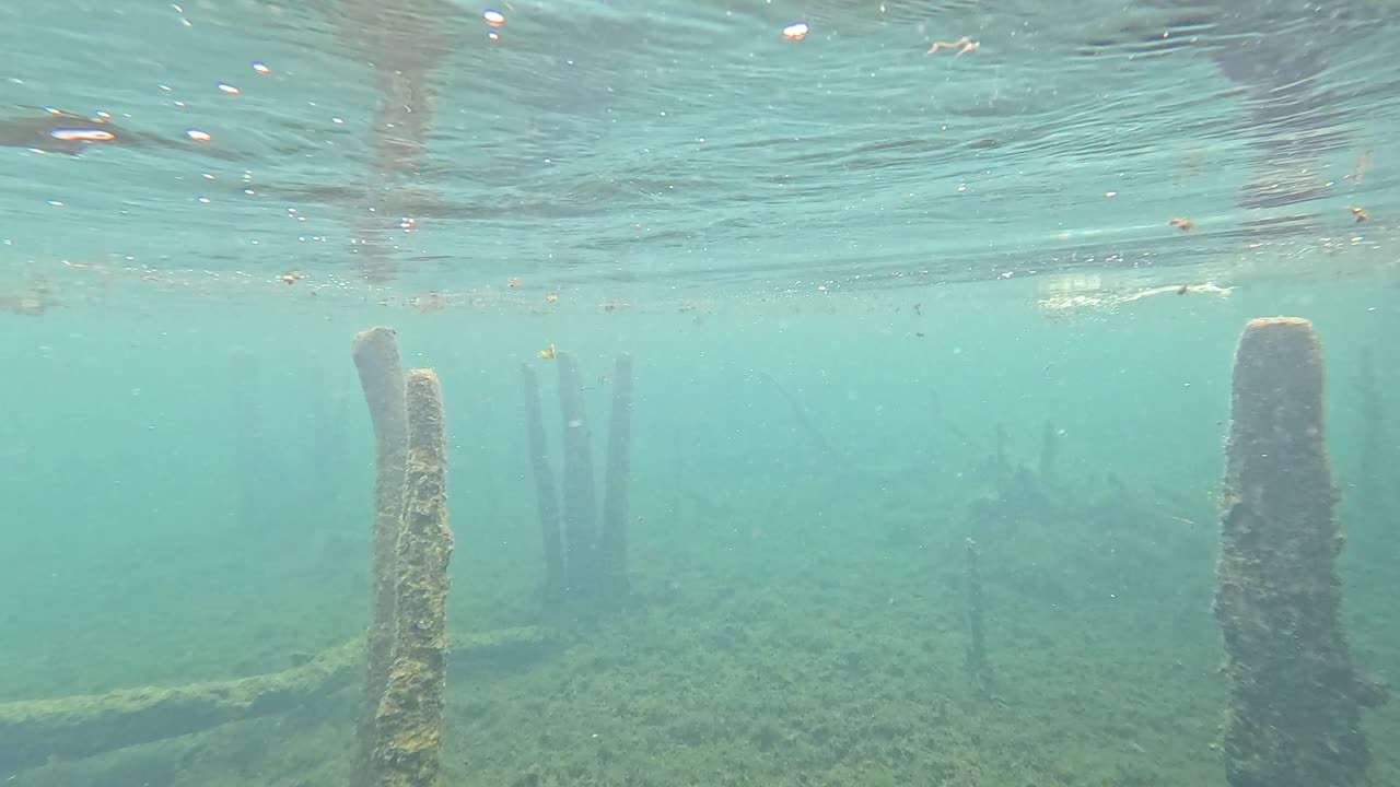 vista submarina de un lago con estructuras de madera sumergidas y escombros