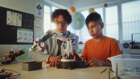student and teacher working on a robot arm in a classroom