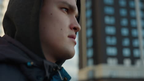 close-up of man wearing jacket and beanie jogging on outdoor sport arena, highlighting focus and determination against urban backdrop with blurred office building