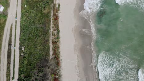 Vista-Aérea-De-Las-Olas-Rodando-Sobre-La-Orilla-Arenosa