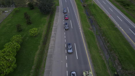 clip de avión no tripulado por encima del camión superando una cola de coches, moviéndose a lo largo de dos líneas de carretera de carril con hierba y arbustos