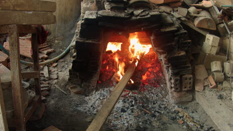 Ein-Asiatischer-Holzofen,-In-Dem-Schürhaken-Und-Feuer-Brennen,-Zeigt-Traditionelle-Töpfermethoden-Und--kultur