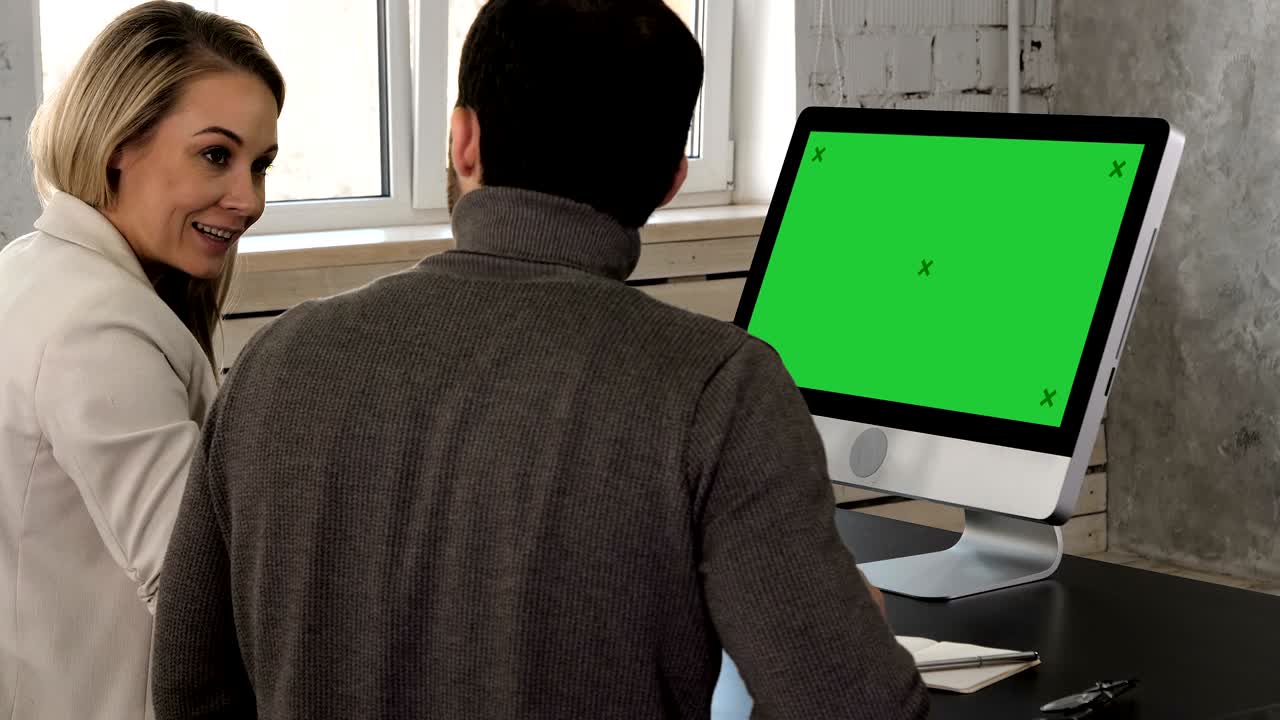 dos jóvenes empresarios teniendo una reunión en la oficina mirando en el monitor. pantalla verde muestra de maqueta