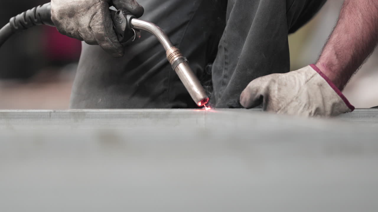 A Skilled Male Worker Wearing Gloves Holding A Welding Gun Welding The ...