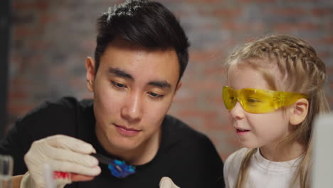 asian teacher shows litmus test to girl at science lesson