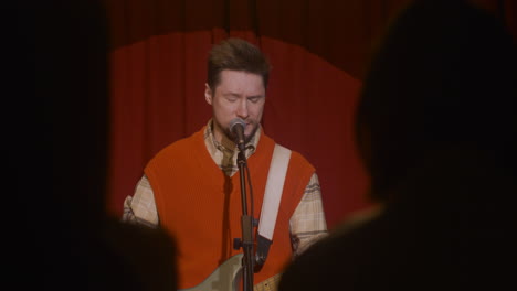 male musician playing guitar and singing during live music perfomance 4