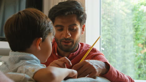 Padre-E-Hijo-En-Casa-En-El-Sofá-Del-Salón-Jugando-Juntos-Con-Un-Juego-De-Dibujo