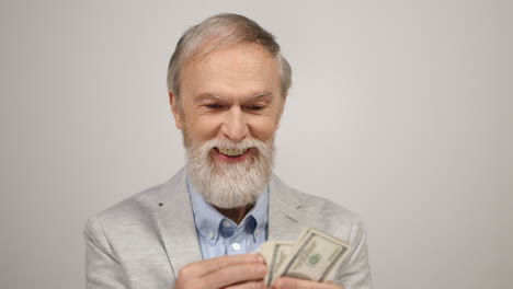 Successful-old-man-having-money-in-studio.-Smiling-guy-counting-dollars-indoors.